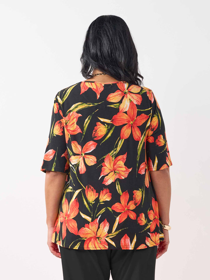 back view of model wearing a black short-sleeve top with a vibrant orange and red floral print
