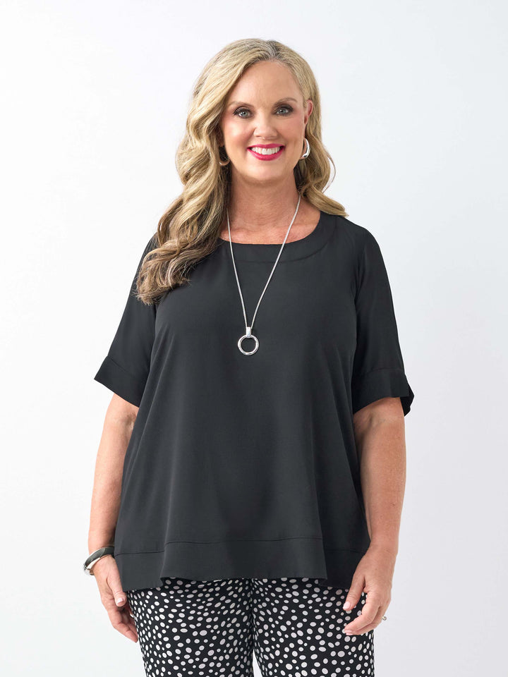 a woman wearing a plain black bubble textured short sleeve top