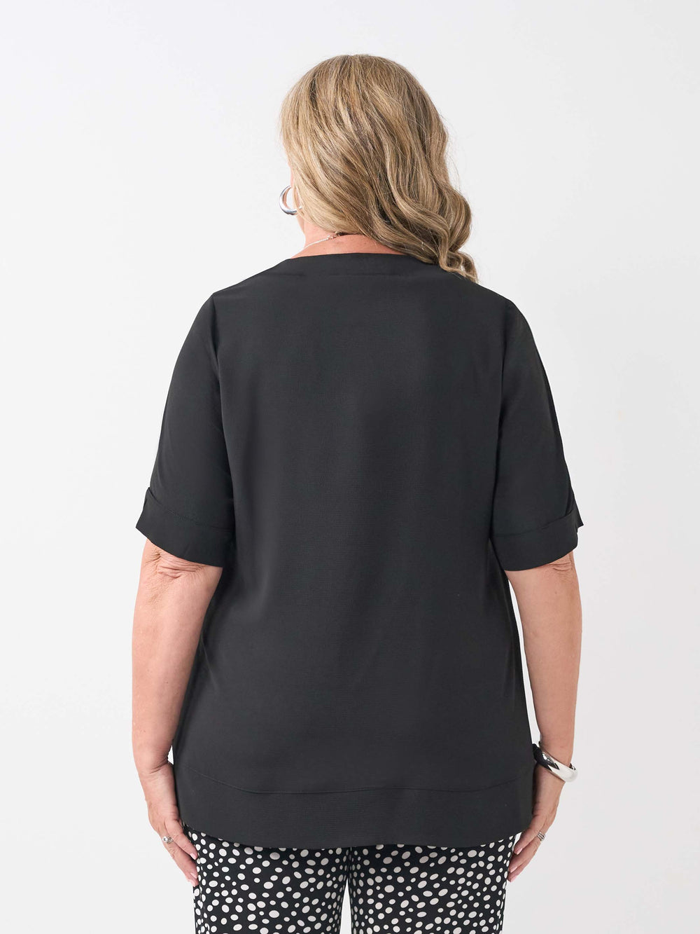 a back view of a woman wearing a plain black bubble textured short sleeve top