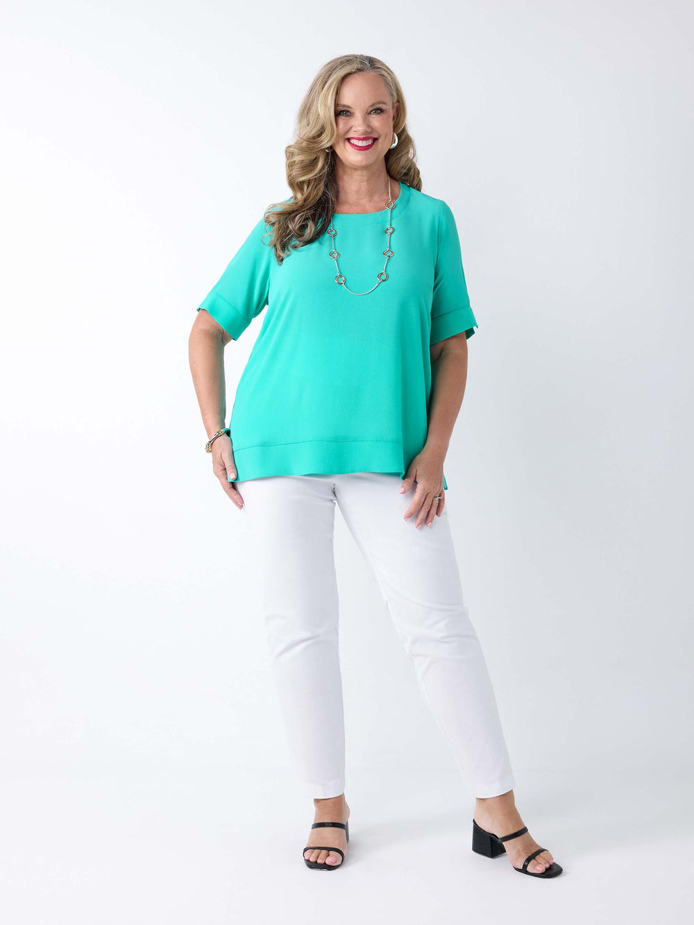 woman wearing a light mist green bubble textured top styled with a pair of white pant