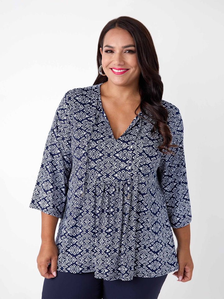 A woman wearing a navy blue and white printed top with three-quarter sleeves and front tie