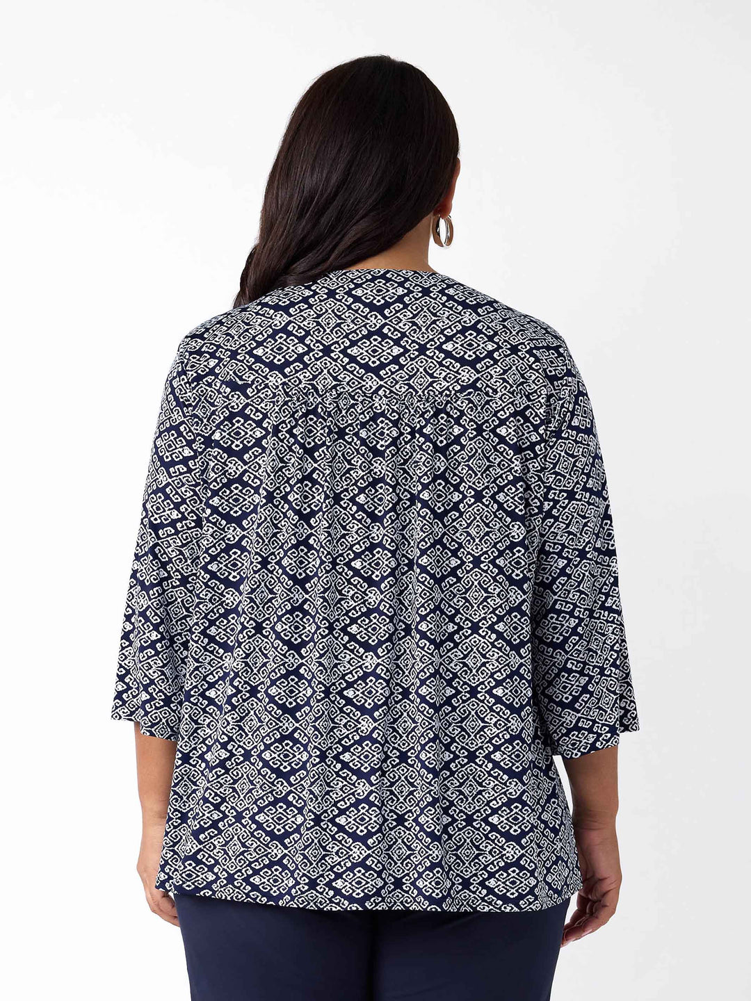 A back view of a woman wearing a navy blue and white printed top with three-quarter sleeves