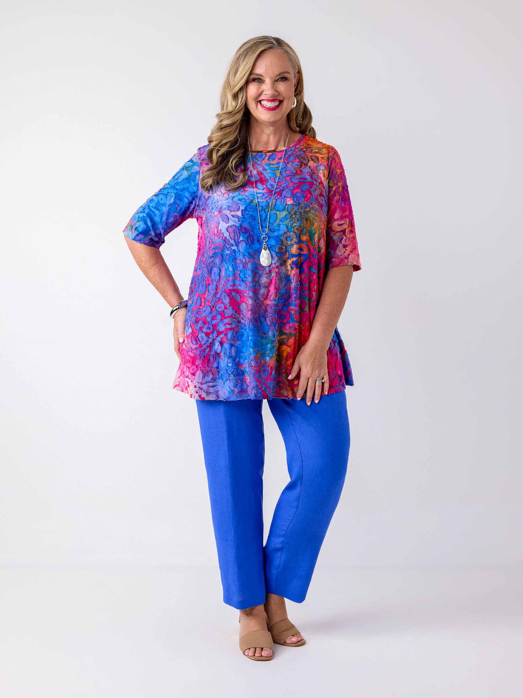 woman wearing a colourful swing jersey top with blue and pink tone print with burnout detail, paired with blue pants