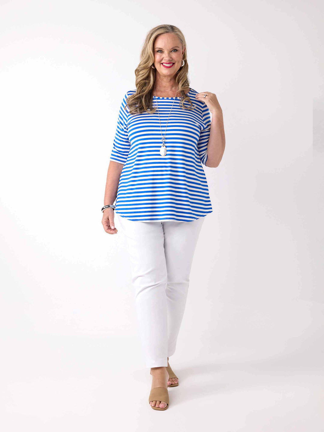 A woman wearing a cobalt blue and white striped short-sleeve top with white pants