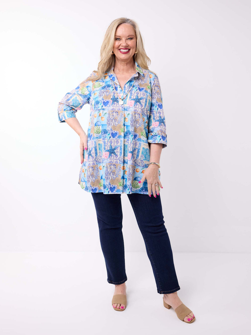 a woman wearing a collared cotton top with blue tropical resort print, featuring a three-quarter sleeves with tab details