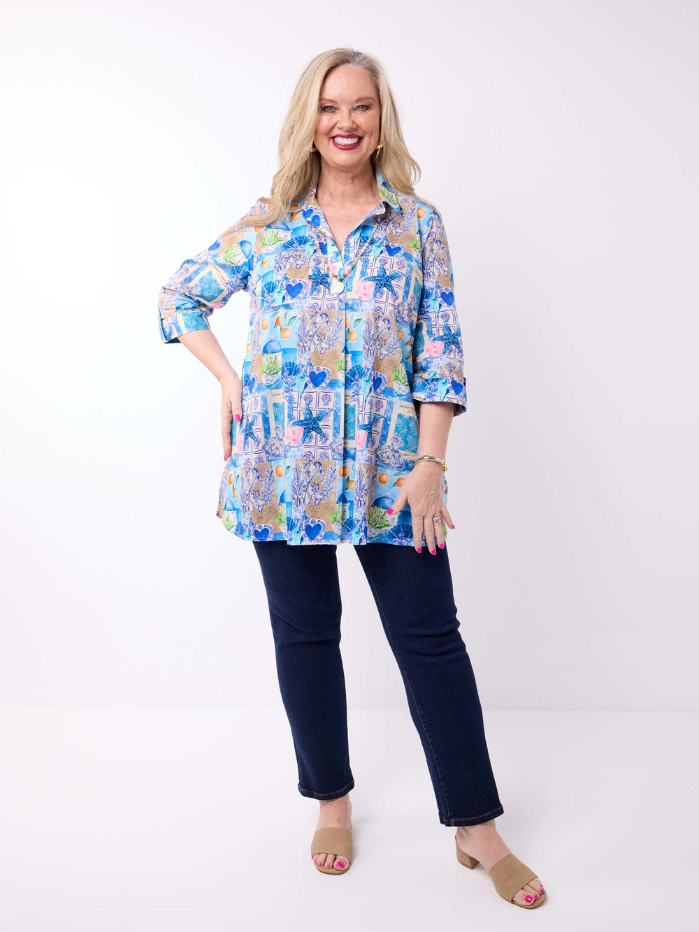 a woman wearing a collared cotton top with blue tropical resort print, featuring a three-quarter sleeves with tab details