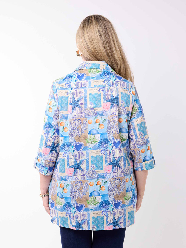 a woman wearing a collared cotton top with blue tropical resort print, featuring a three-quarter sleeves with tab details