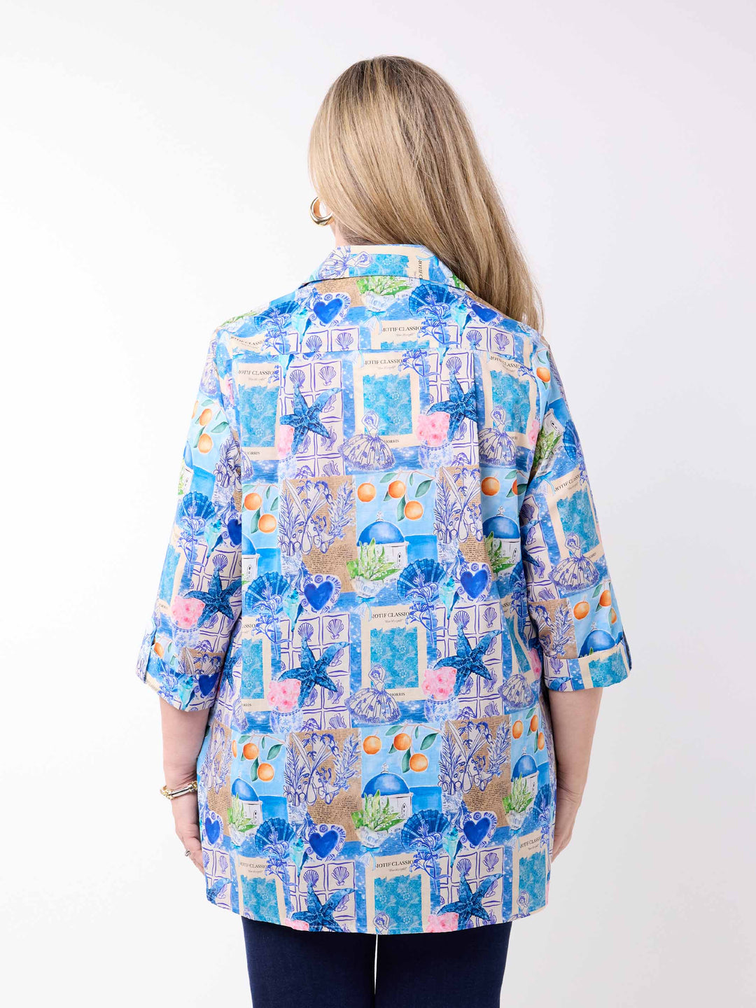 a woman wearing a collared cotton top with blue tropical resort print, featuring a three-quarter sleeves with tab details