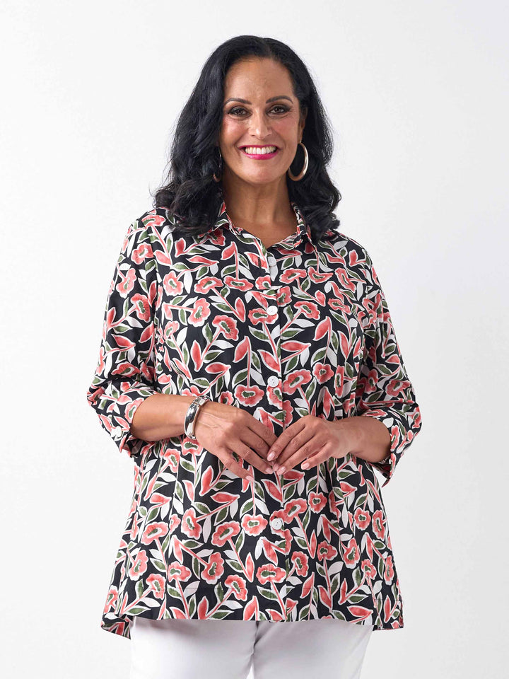 model wearing a button-up collared cotton shirt with a red and green floral print
