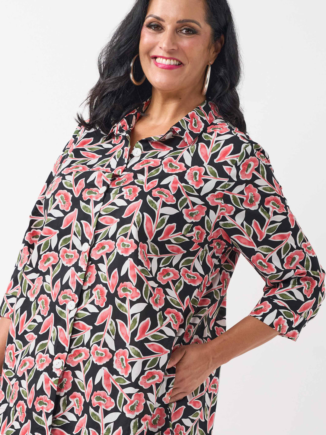 detail view of model wearing a button-up collared cotton shirt with a red and green floral print and side pockets