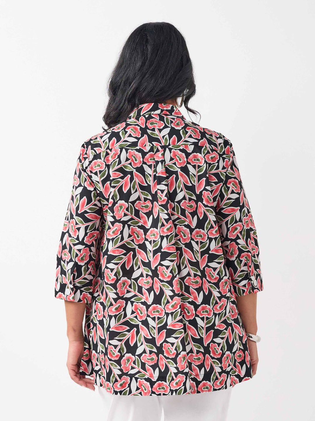 back view of model wearing a button-up collared cotton shirt with a red and green floral print