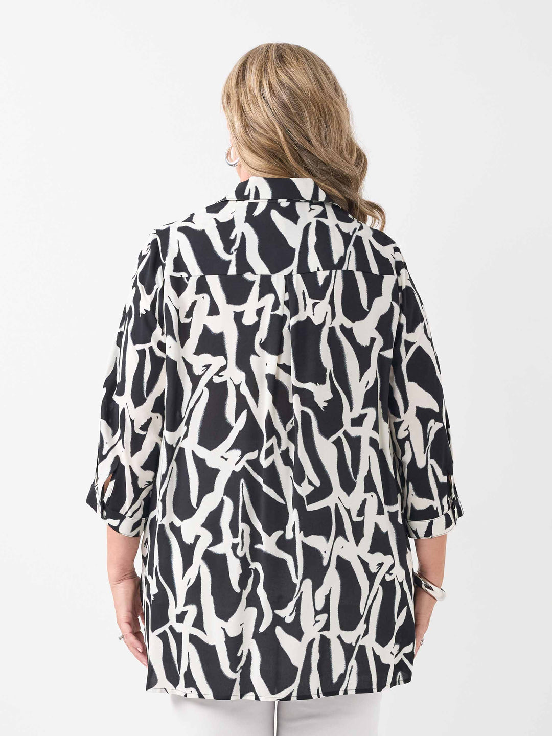 back view of model wearing a black and white abstract printed button-up shirt with three-quarter sleeves and white pants
