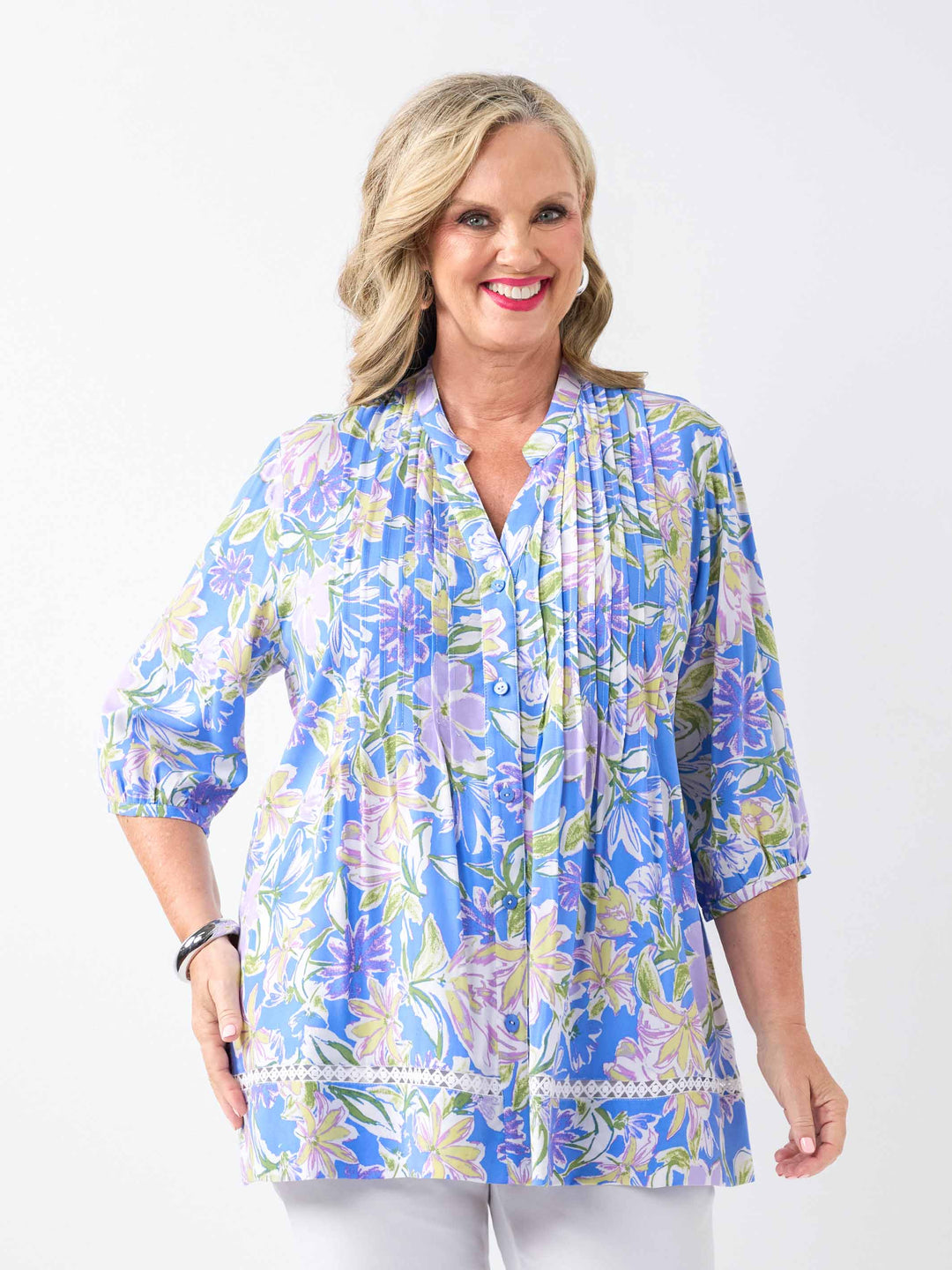 A woman wearing a blue floral printed button through top with pintuck detail at front and lace around the hem