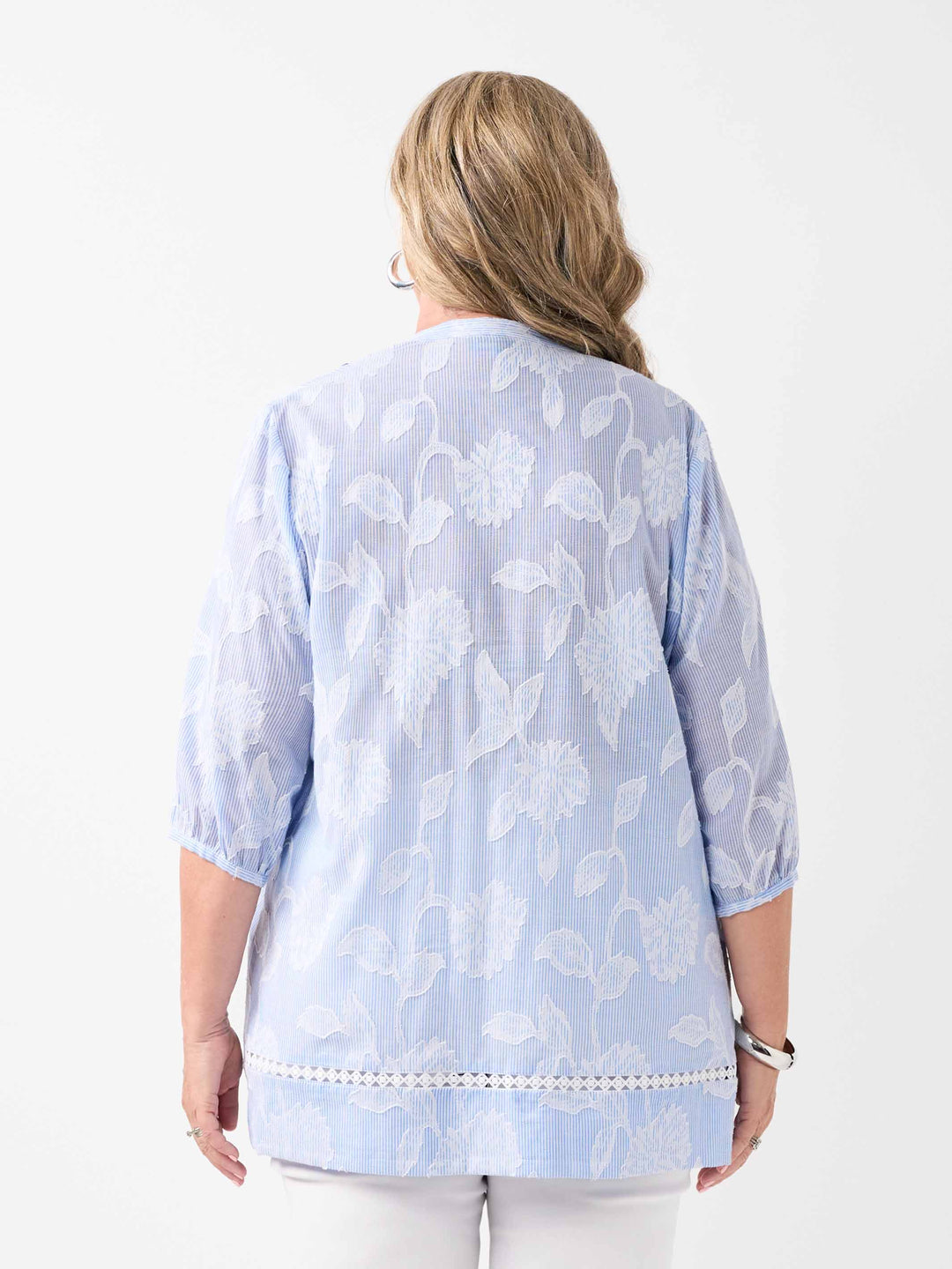 A woman viewed from the back wearing a ticking stripe shirt with white floral flocked design on a ticking stripe