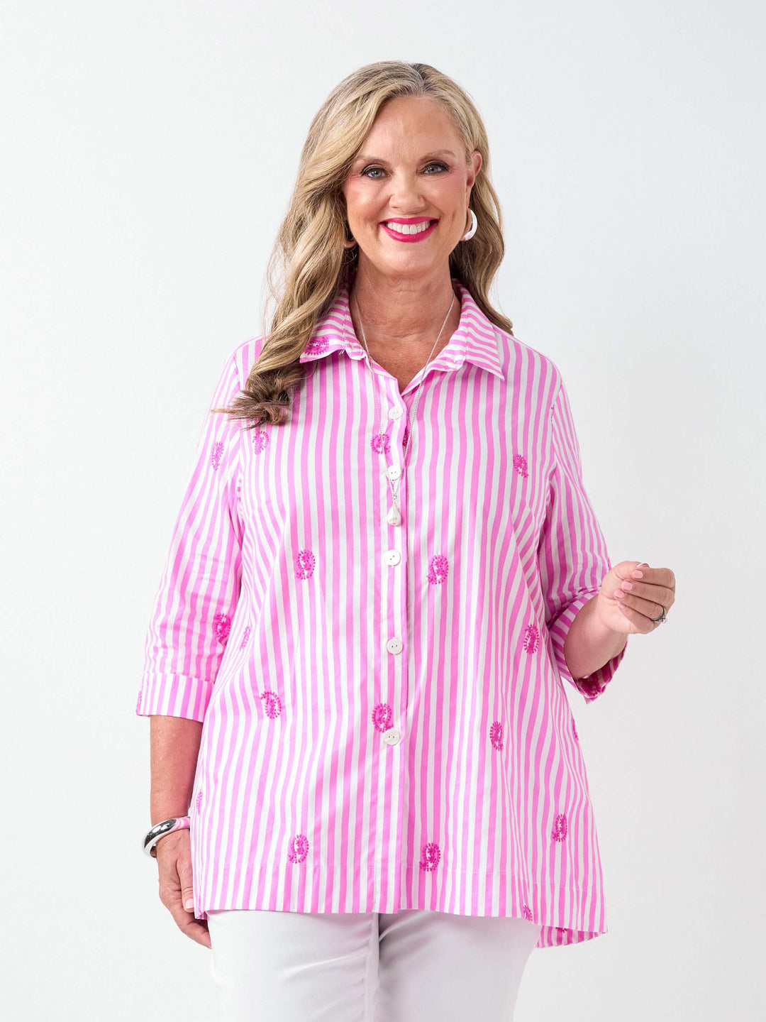 A woman wearing a pink and white striped button-up collared cotton shirt with embroidered pink paisley details