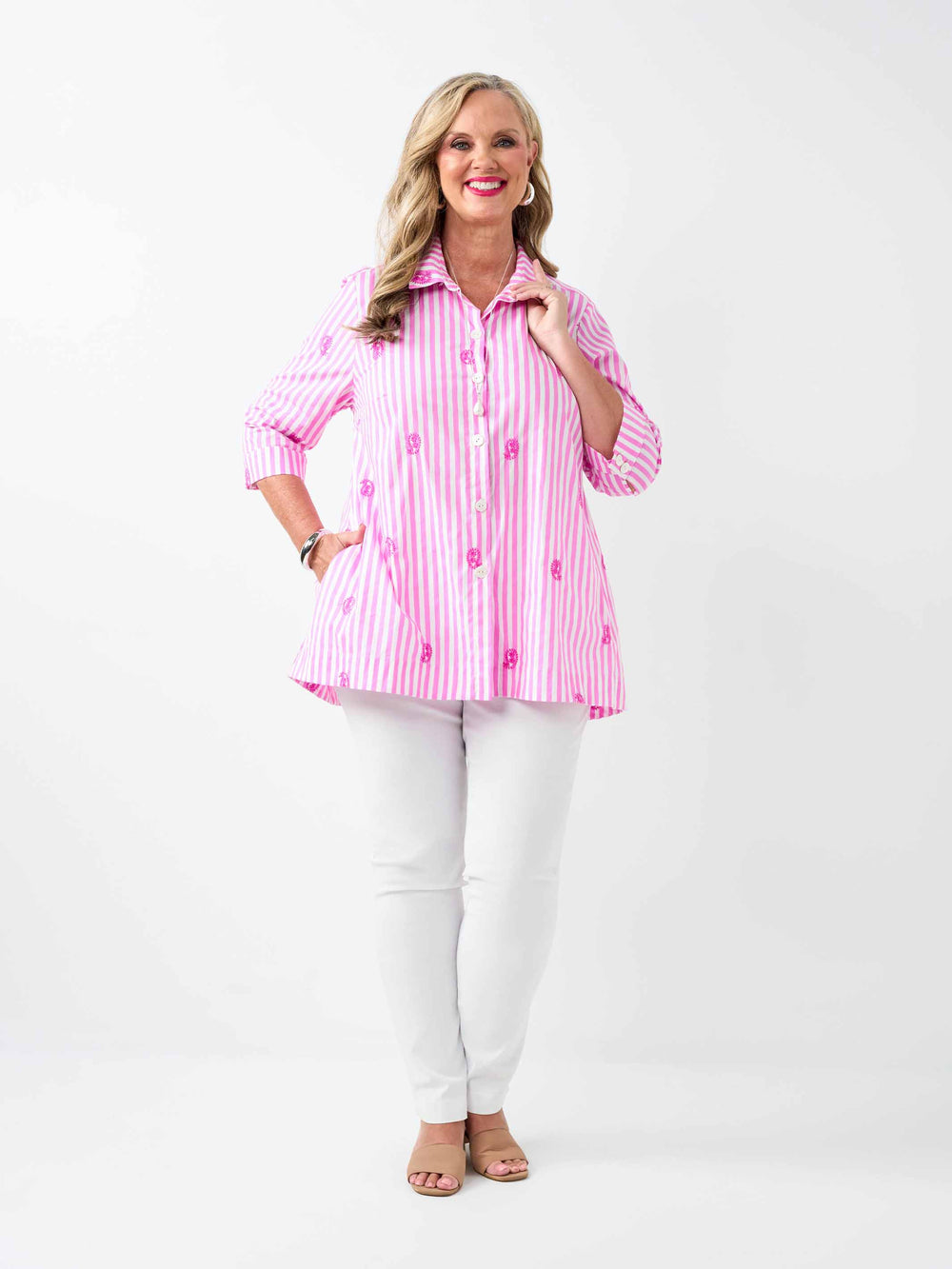 A woman wearing a pink and white striped button-up collared cotton shirt with embroidered pink paisley details
