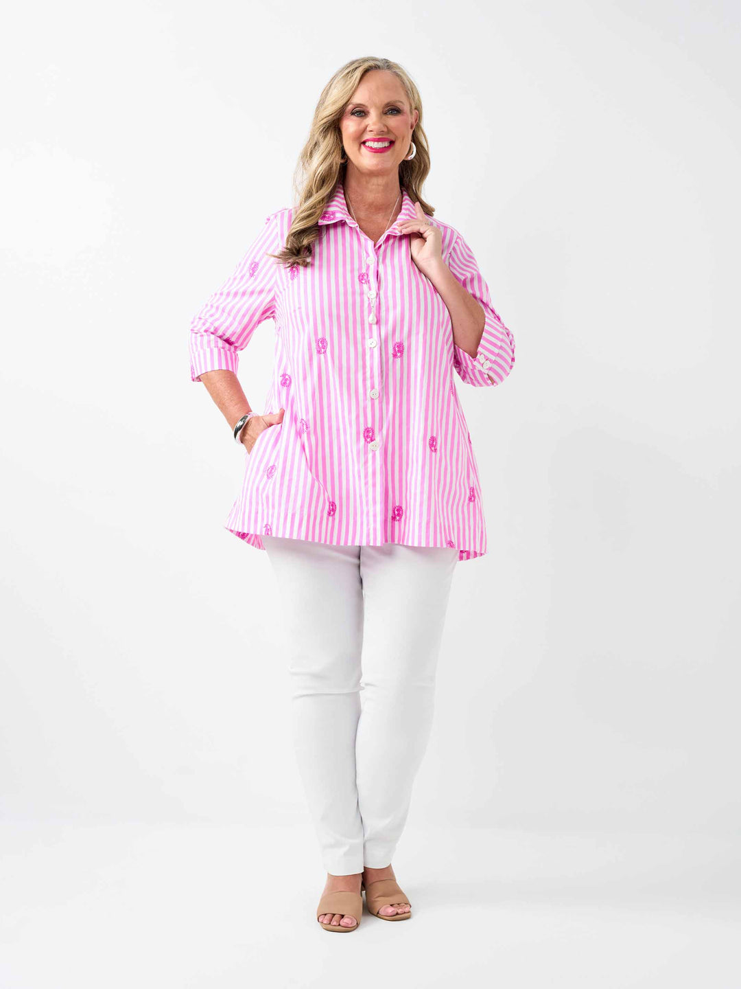 A woman wearing a pink and white striped button-up collared cotton shirt with embroidered pink paisley details