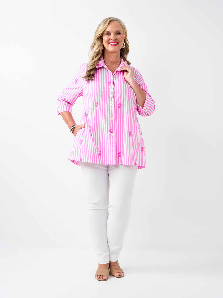 A woman wearing a pink and white striped button-up collared cotton shirt with embroidered pink paisley details