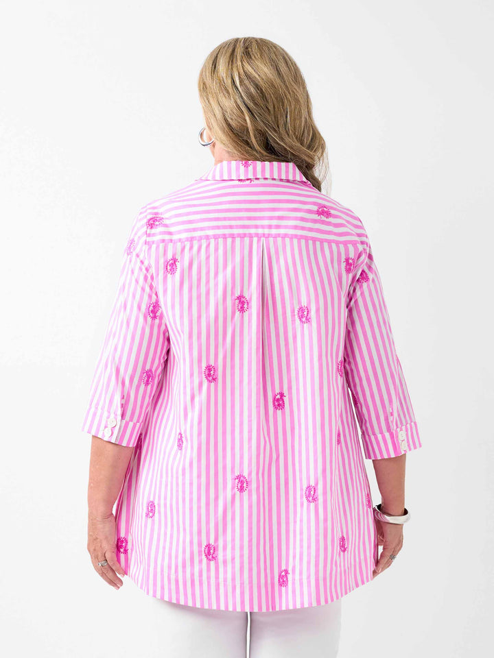 A back view of a woman wearing a pink and white striped button-up collared cotton shirt with embroidered pink paisley details