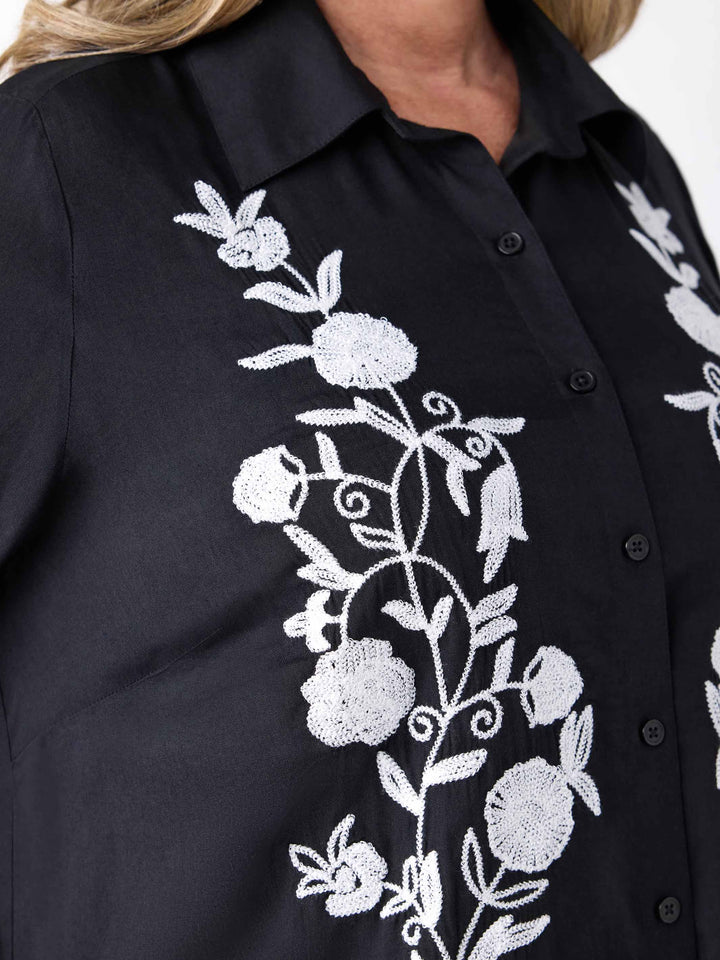 a black button-up shirt with white floral embroidery detail on the front
