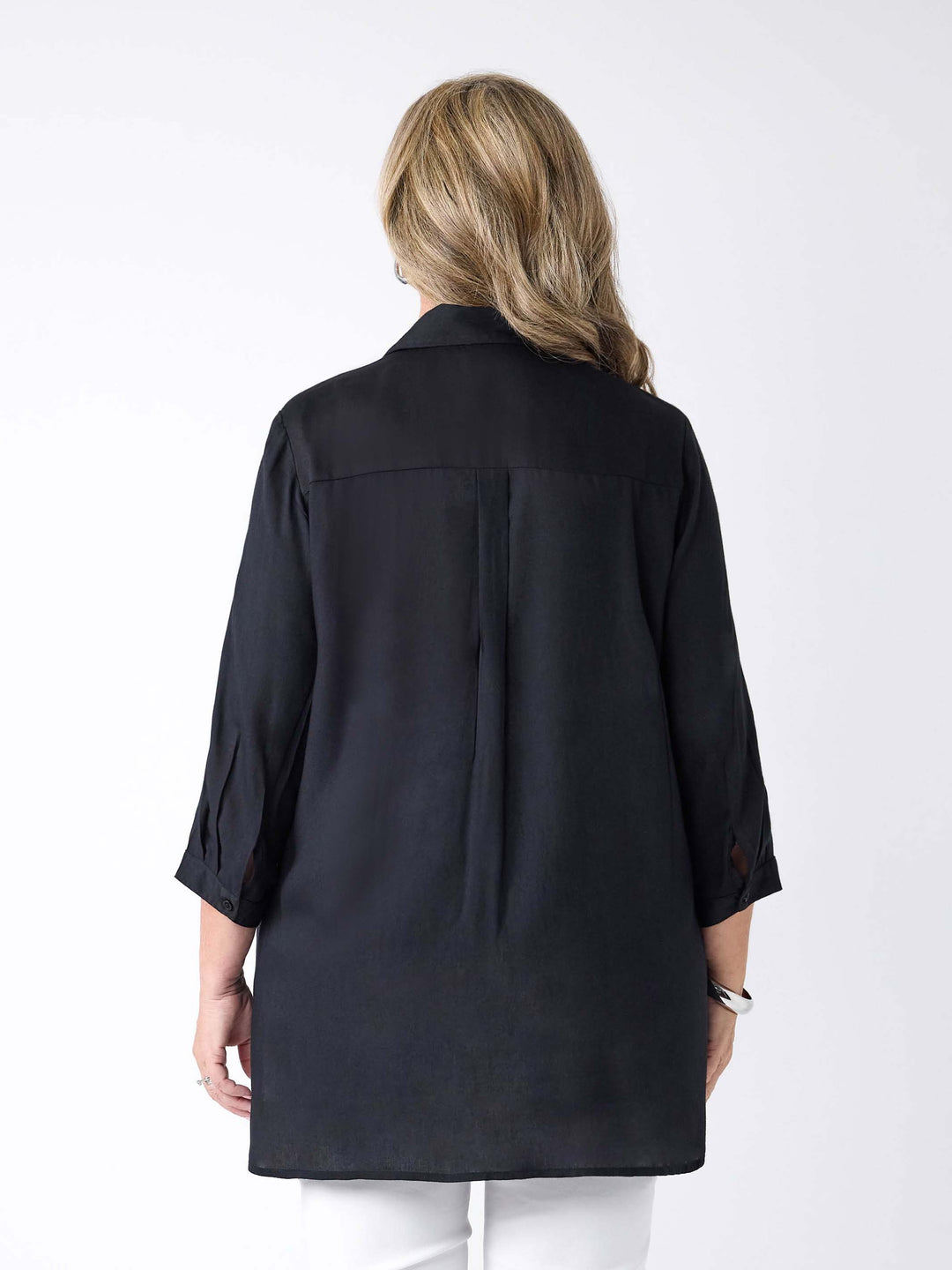 A woman viewed from the back wearing a black shirt paired with white pants.