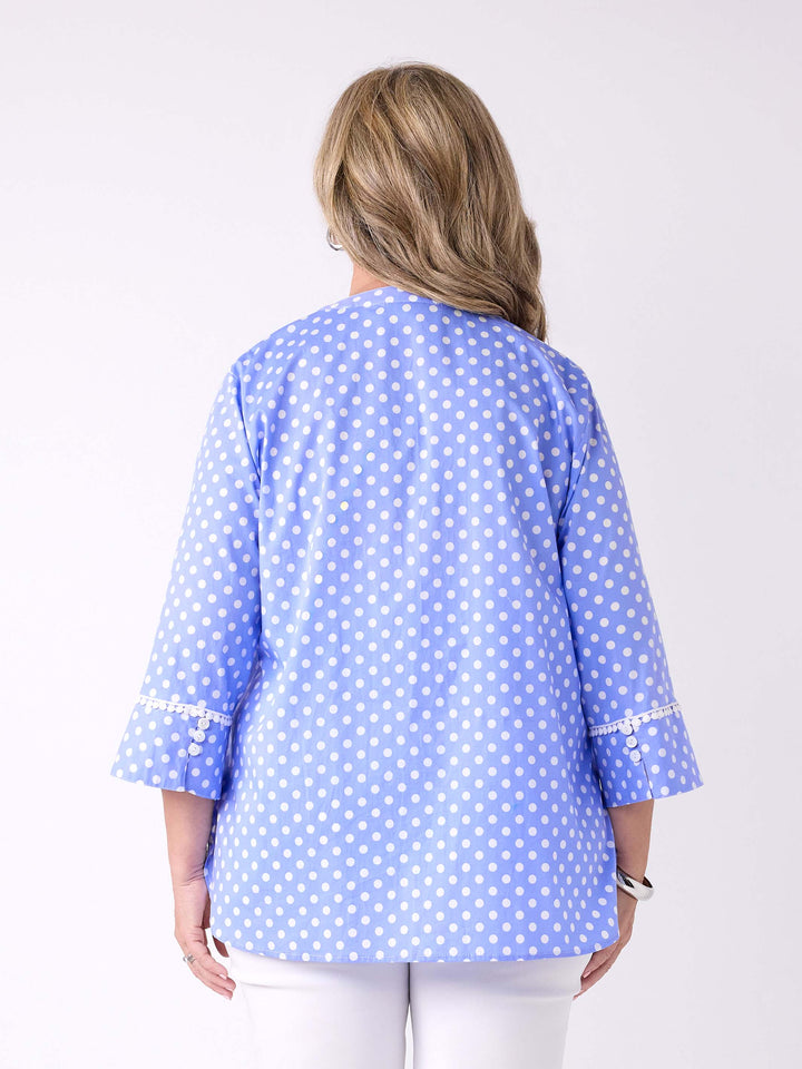 A woman viewed from the back wearing a light blue button-front blouse with white polka dots and white pants