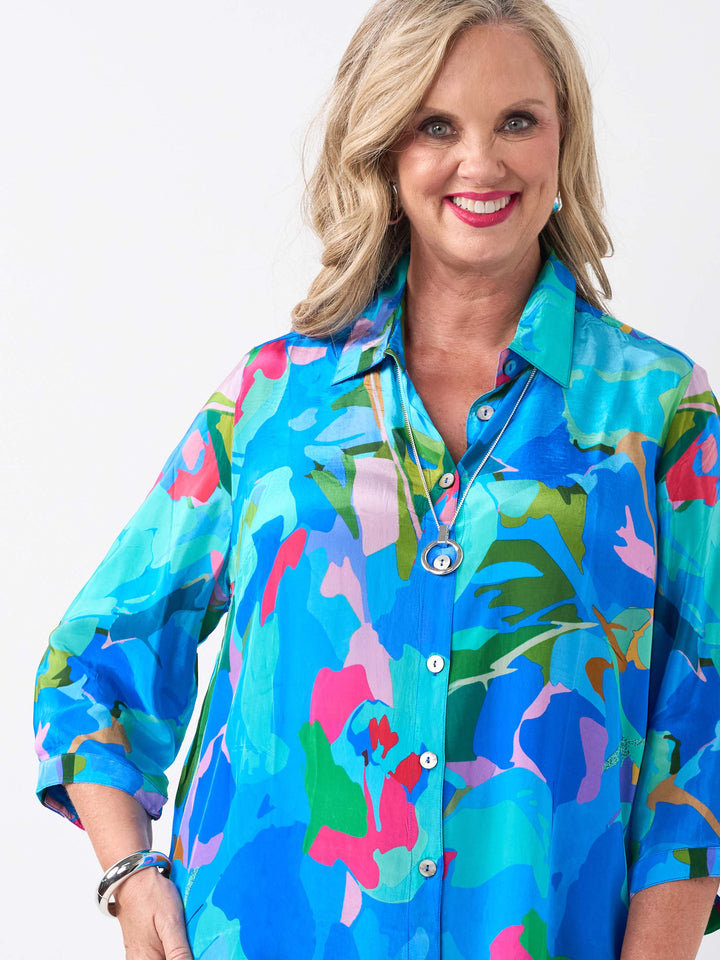 A woman wearing a vibrant multicolour printed collared shirt in different shades of blue, paired with cobalt linen pant