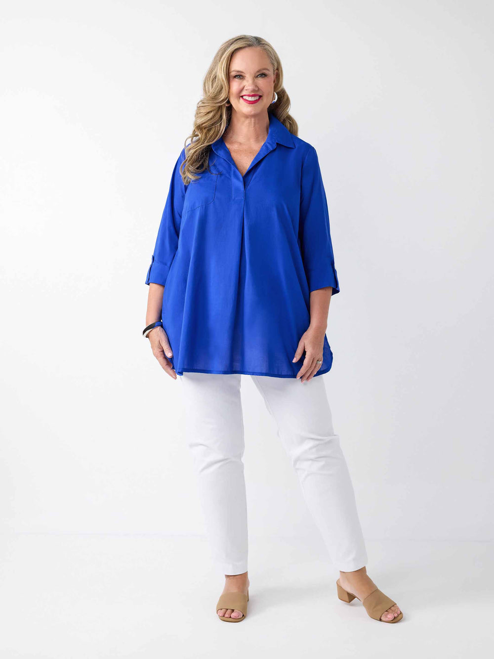 model wearing a bright royal blue collared cotton top with three-quarter tab sleeves and white pants