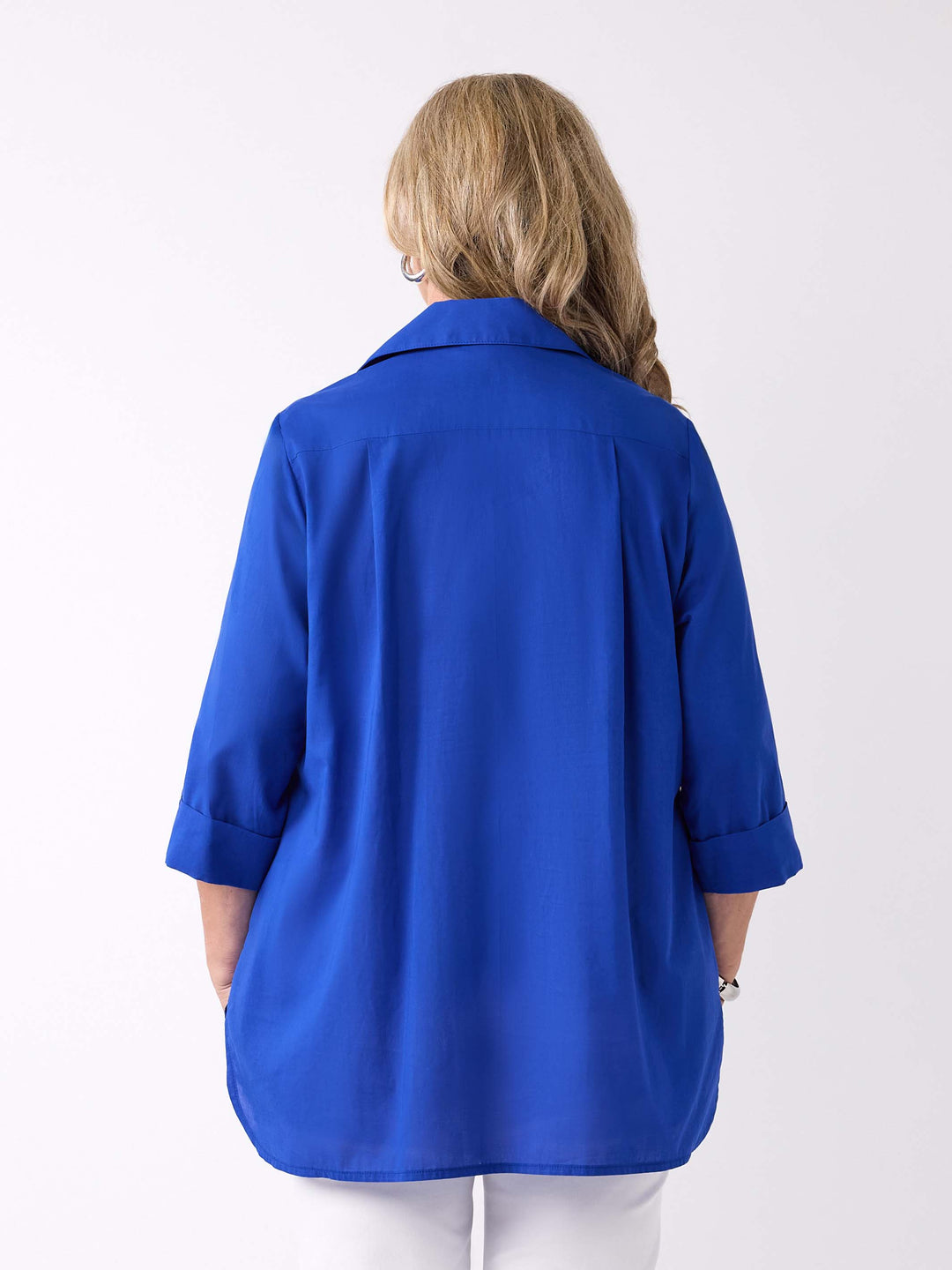 back view of model wearing a bright royal blue collared cotton top with three-quarter tab sleeves and white pants