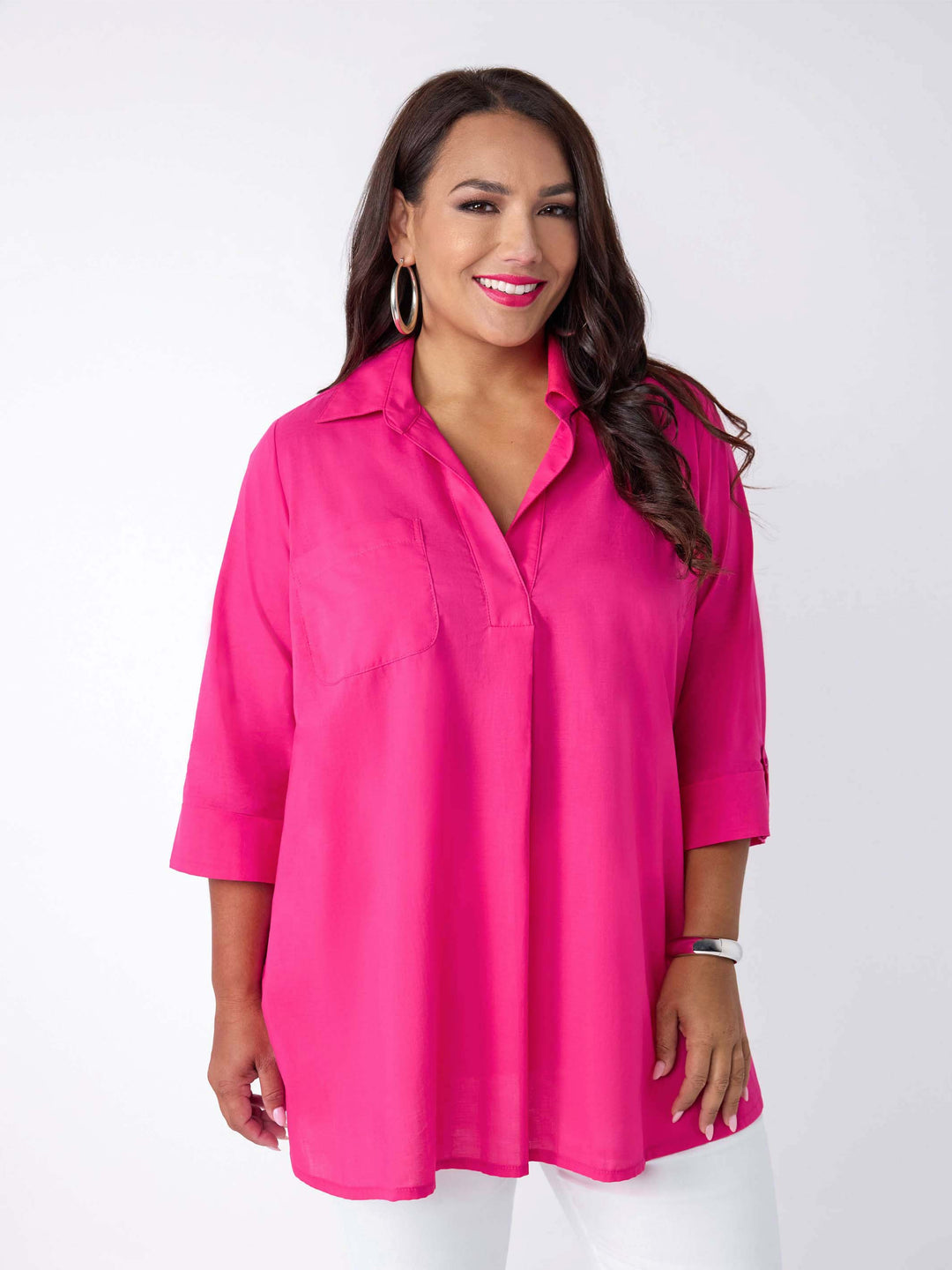 model wearing a bright pink collared top with three-quarter sleeves, paired with white pants