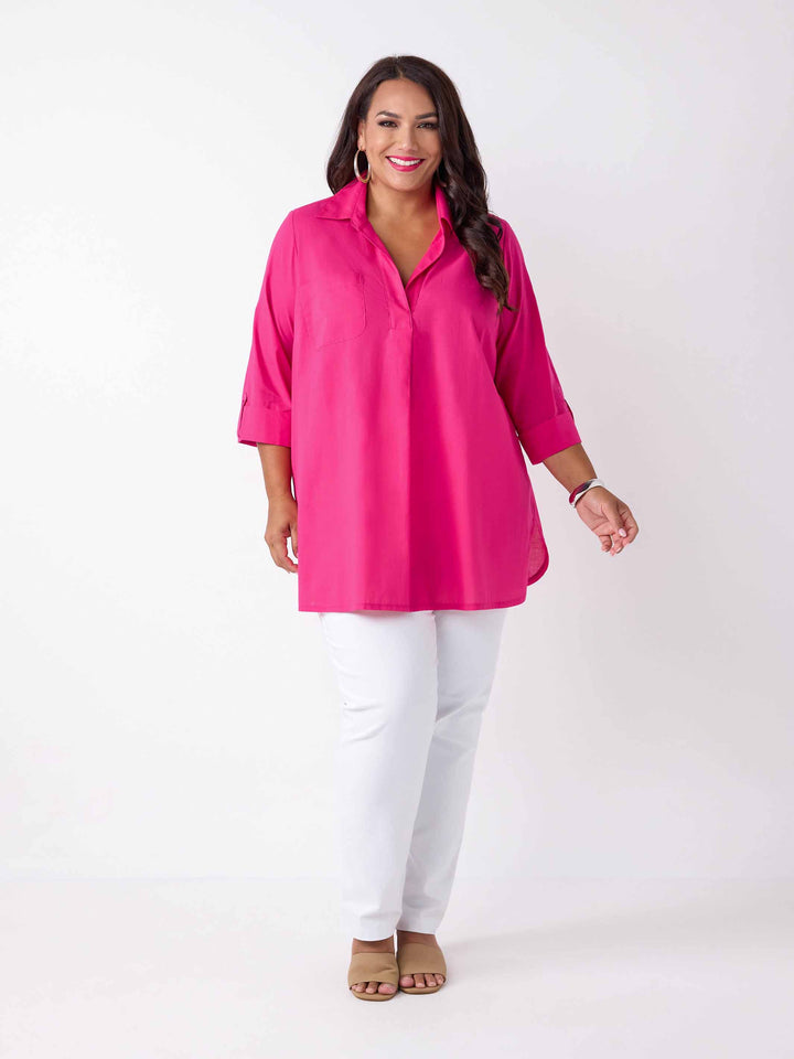 model wearing a bright pink collared top with three-quarter sleeves, paired with white pants