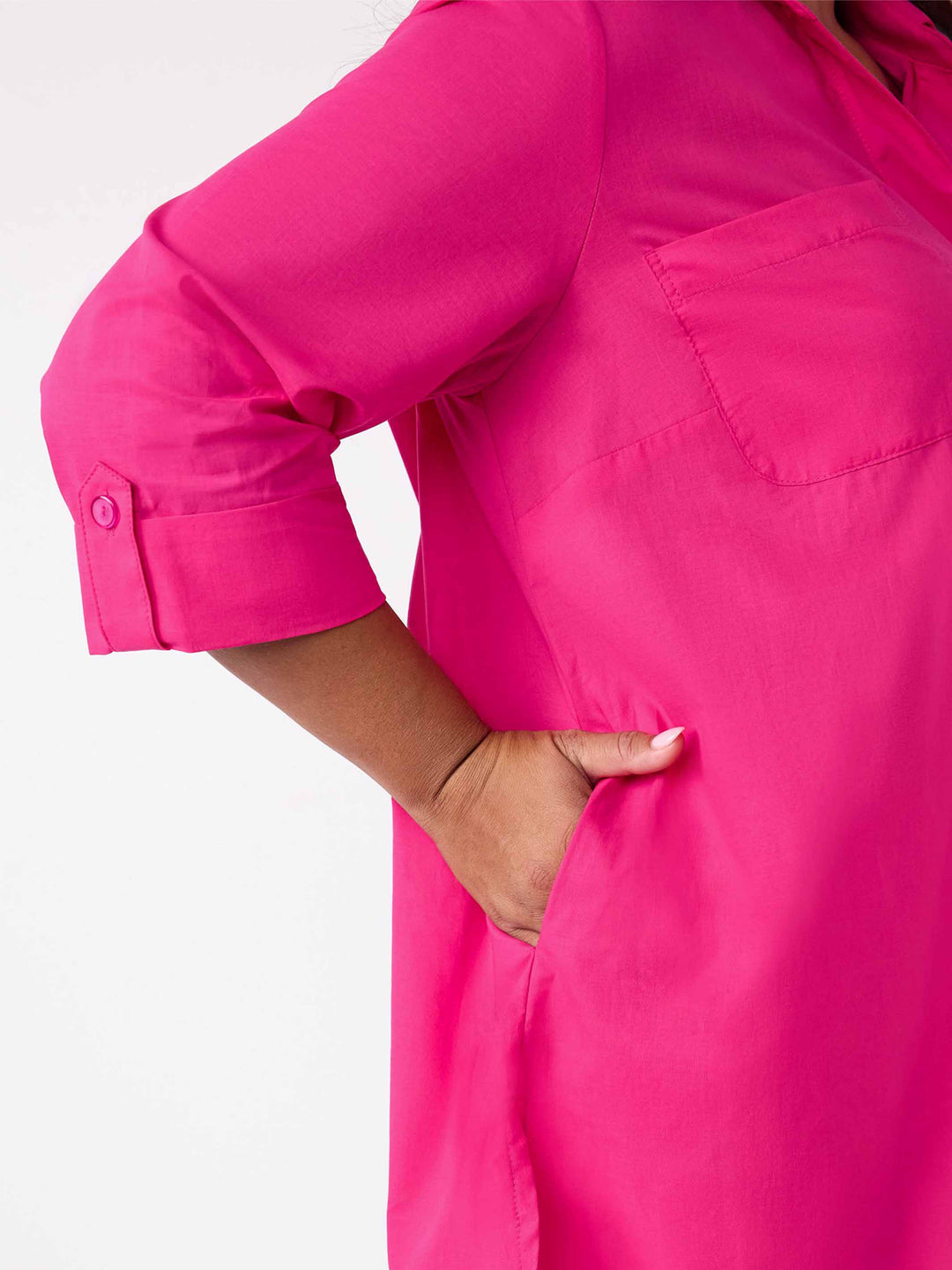 Close-up of a bright pink shirt with a chest pocket and rolled button cuffs