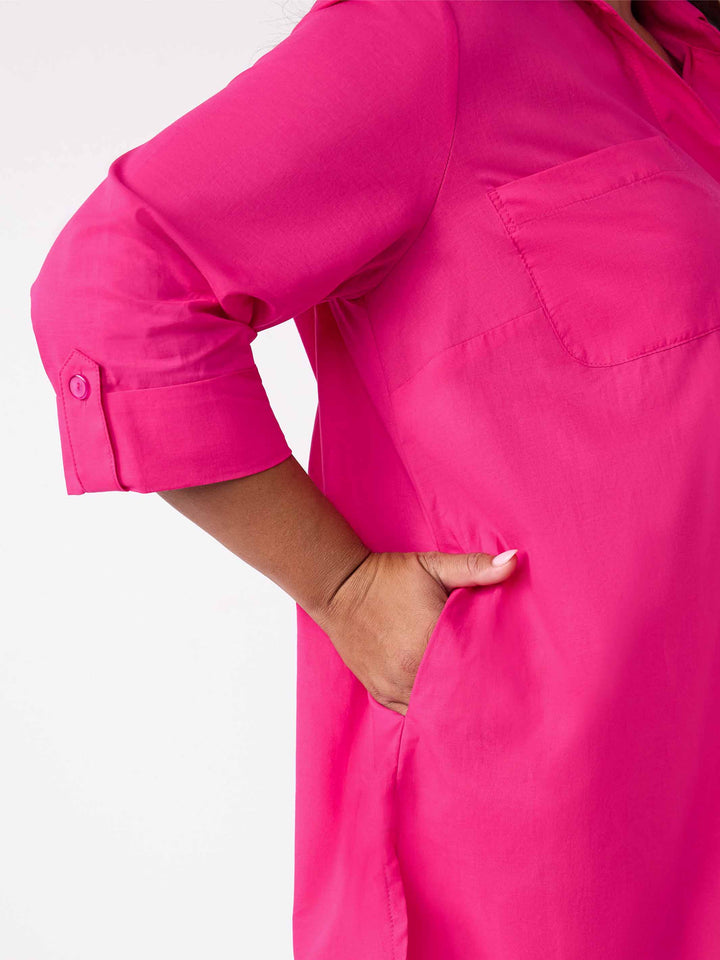 Close-up of a bright pink shirt with a chest pocket and rolled button cuffs