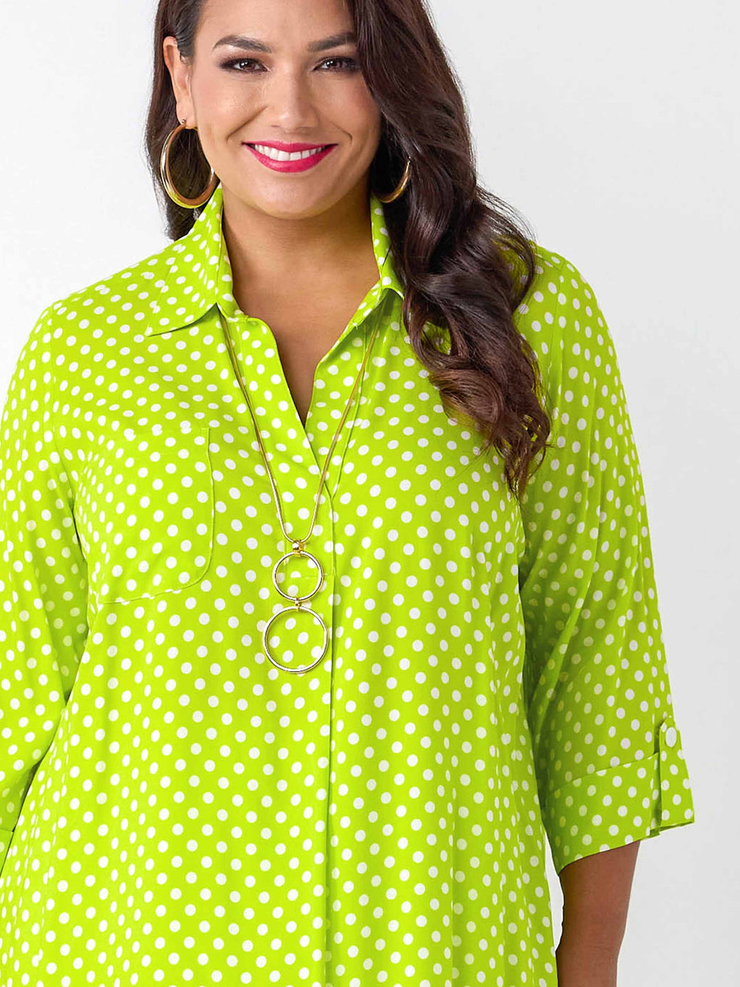 A woman wearing a bright lime green collared top with white polka dots