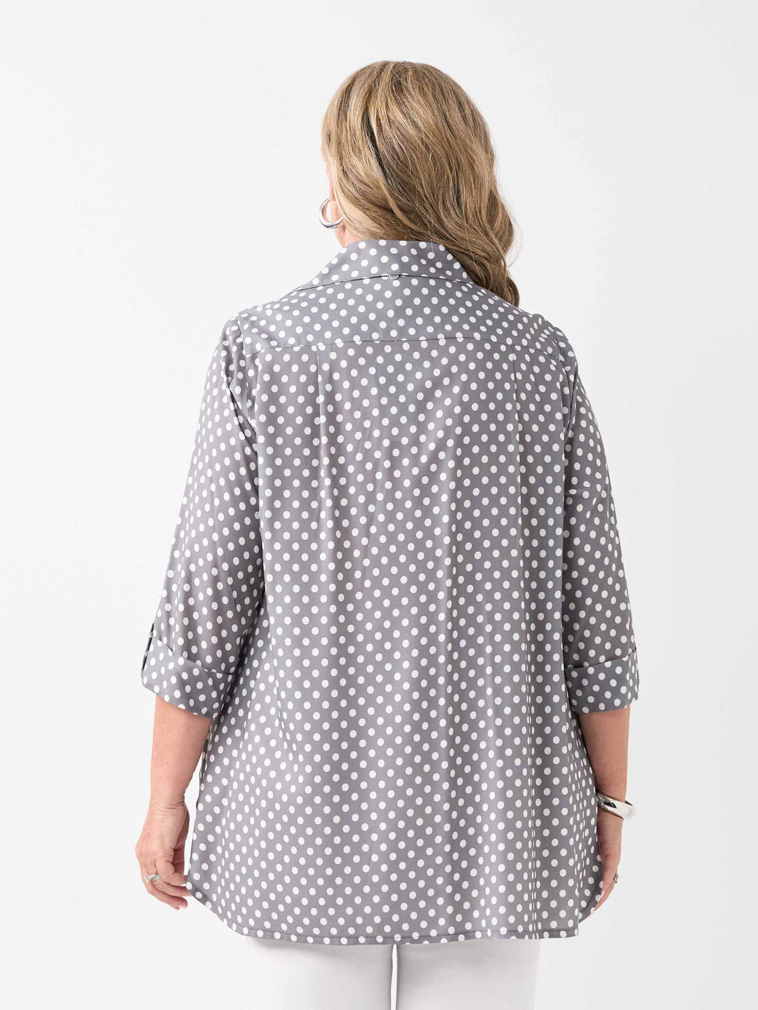 A woman viewed from the back wearing a grey shirt with a white polka dot pattern and white pants