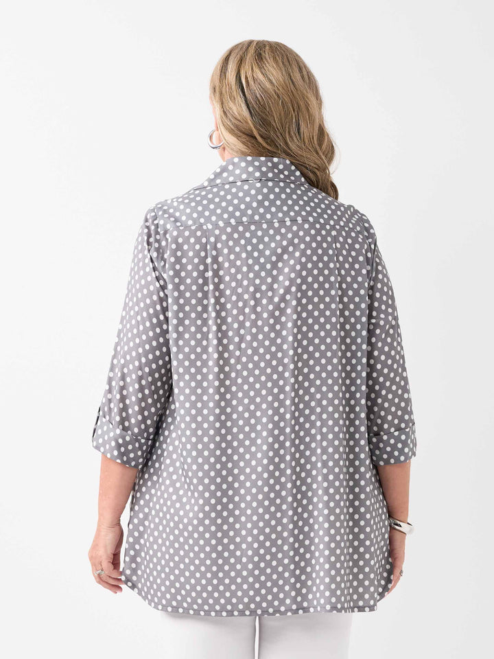 A woman viewed from the back wearing a grey shirt with a white polka dot pattern and white pants