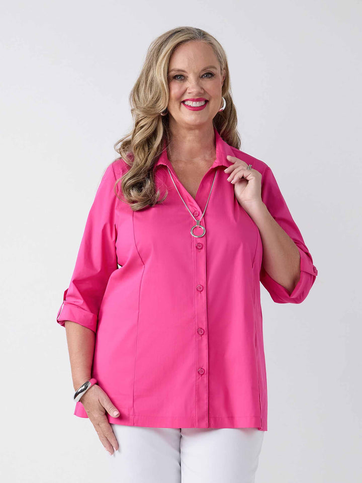 model wearing a bright pink button-up shirt with white pants