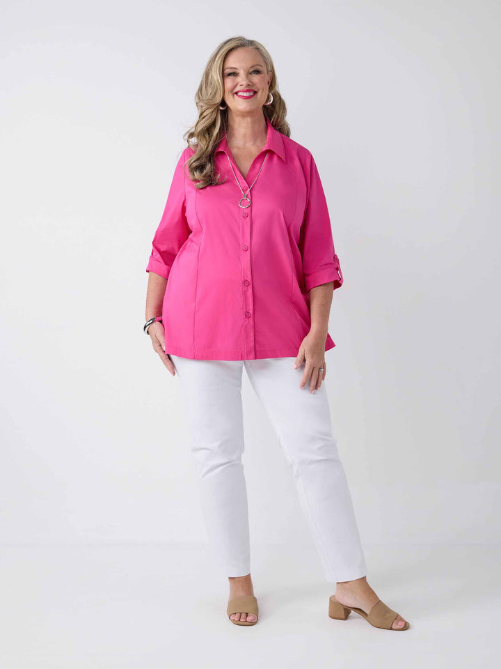 model wearing a bright pink button-up shirt with white pants
