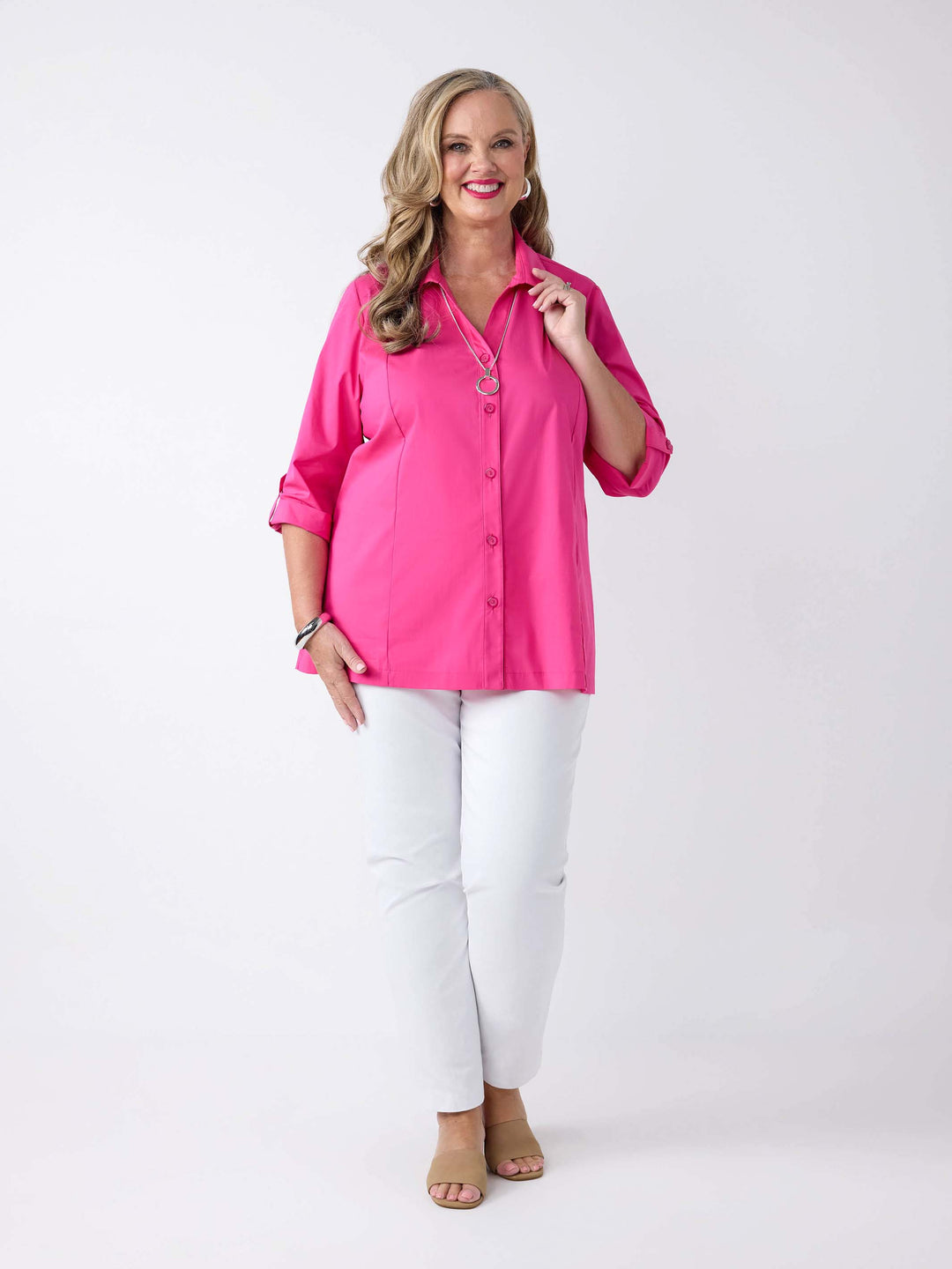 model wearing a bright pink button-up shirt with white pants