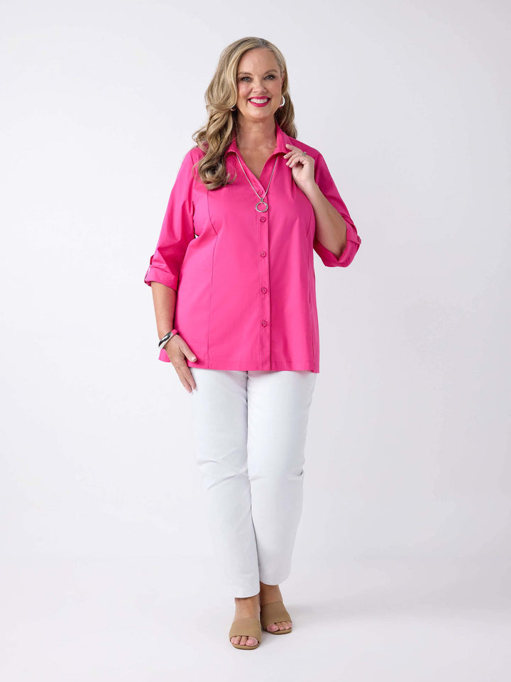model wearing a bright pink button-up shirt with white pants