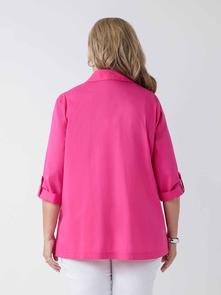 back view of model wearing a bright pink button-up shirt with white pants
