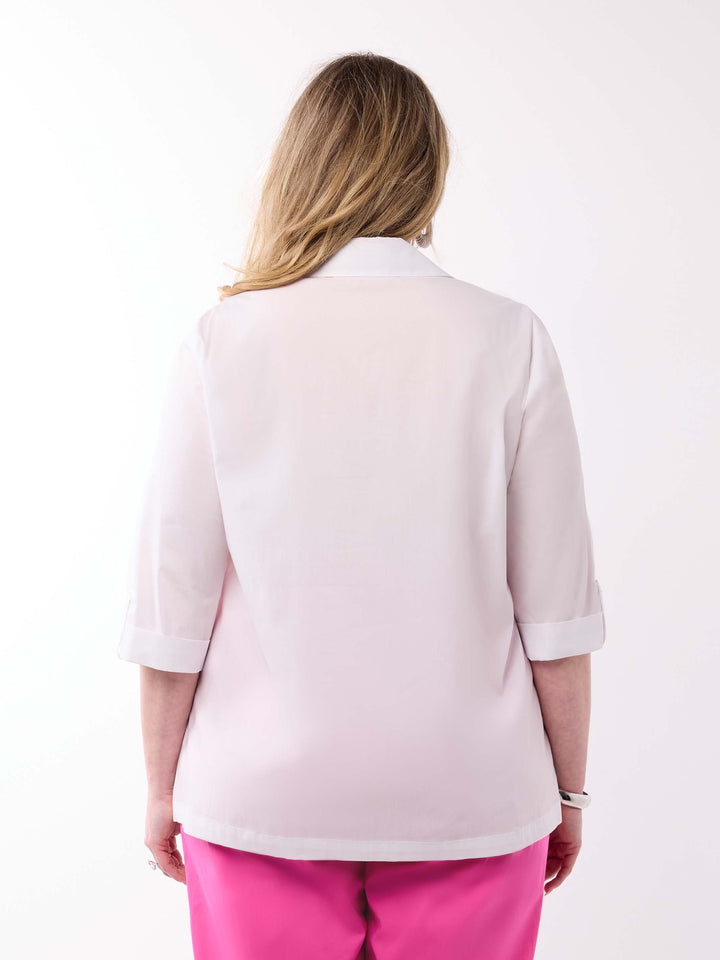 A woman viewed from behind wearing a white shirt with three-quarter tab sleeves and bright pink pants