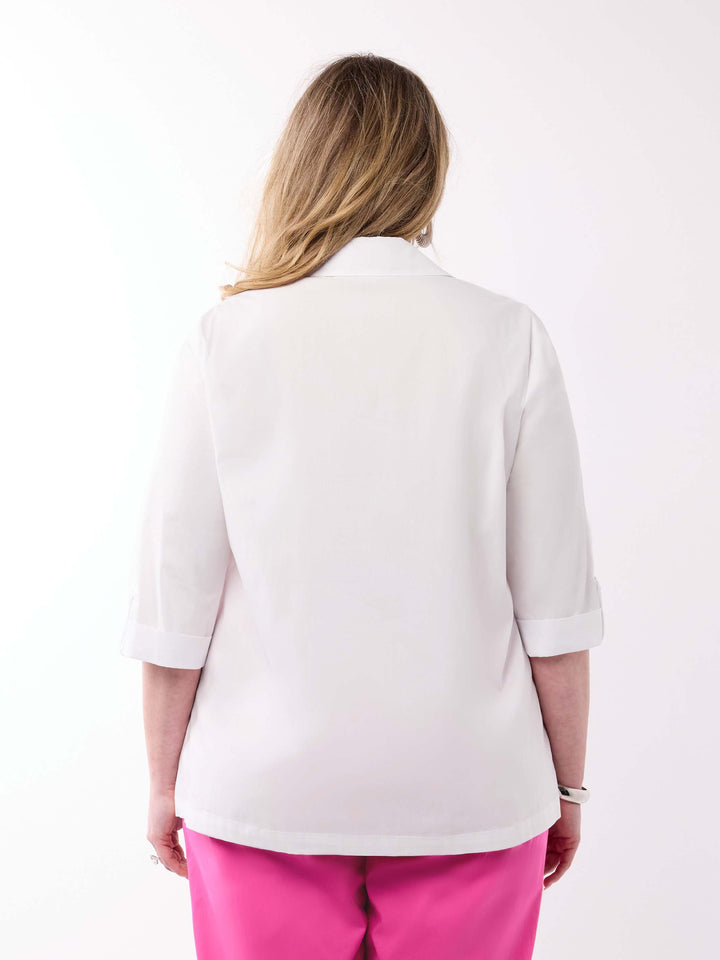 A woman viewed from behind wearing a white shirt with three-quarter tab sleeves and bright pink pants