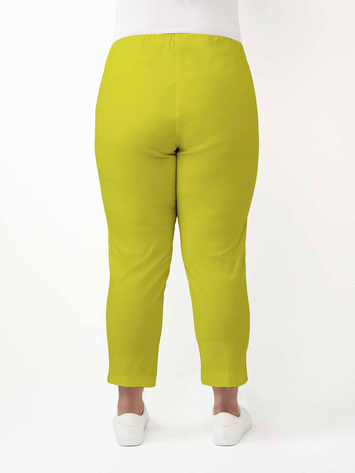 A person shown from the back wearing bright citrus lime green cropped pants