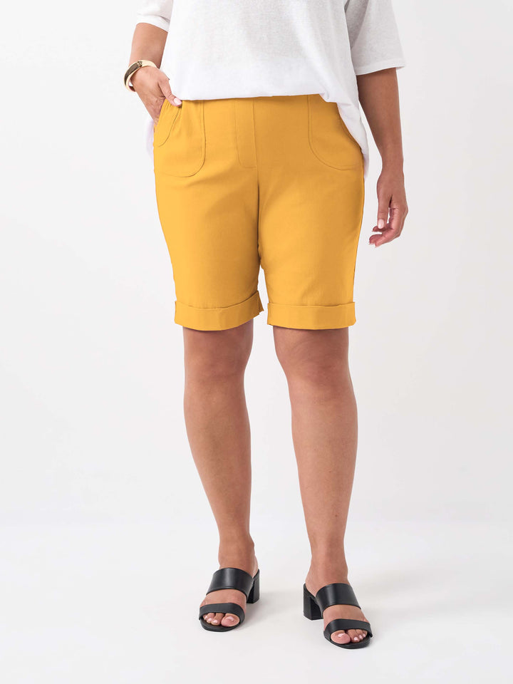 A person wearing a knee length bengaline knee length shorts in vibrant banana yellow with two pockets