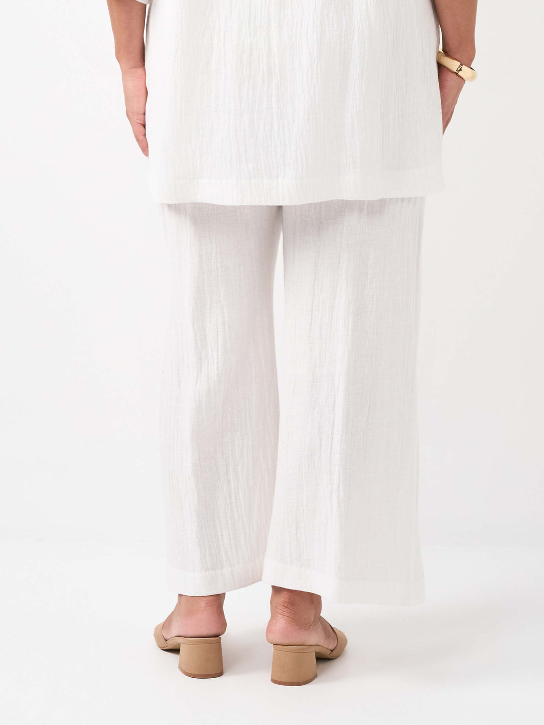 back view of a model wearing a white textured white wide-leg cropped pants, paired with the matching top