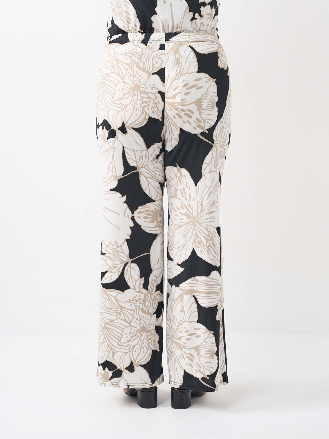 back view of wide-leg palazzo pants featuring a bold beige floral pattern on black base
