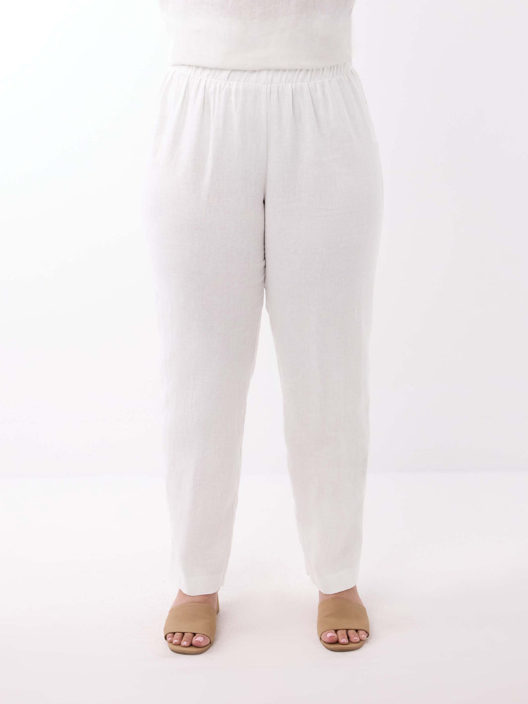 White regular leg linen pants with an elastic waistband, shown on a model from the waist down 