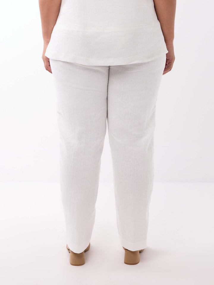 A person shown from the back wearing loose regular leg white pants and a white top