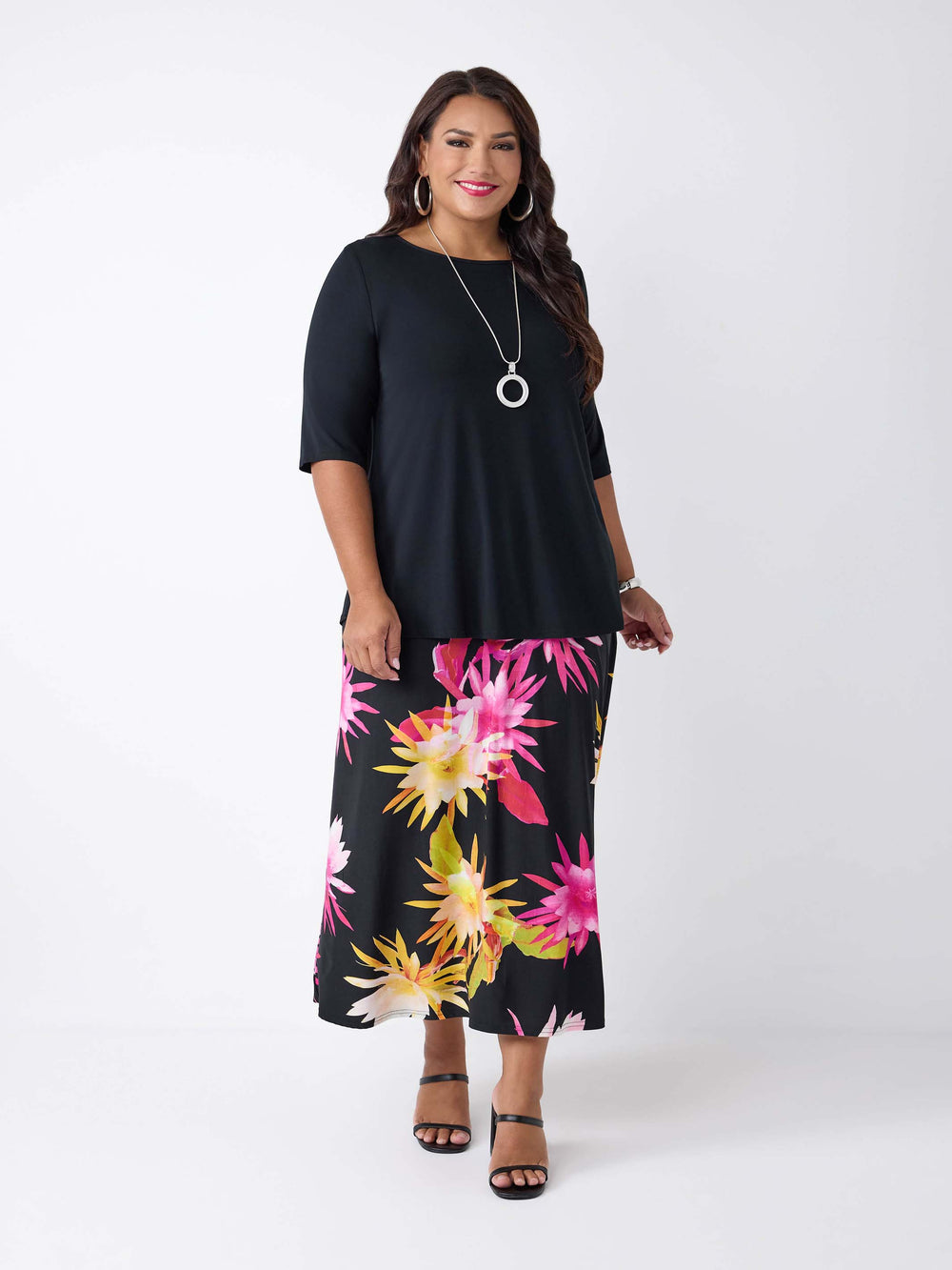 model wearing a black basic t-shirt styled with a black midi skirt with a vibrant, large-scale tropical floral print in pink and yellow
